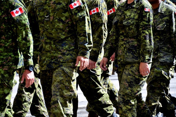 A group of Canadian soldiers wearing green camouflage uniforms march together.