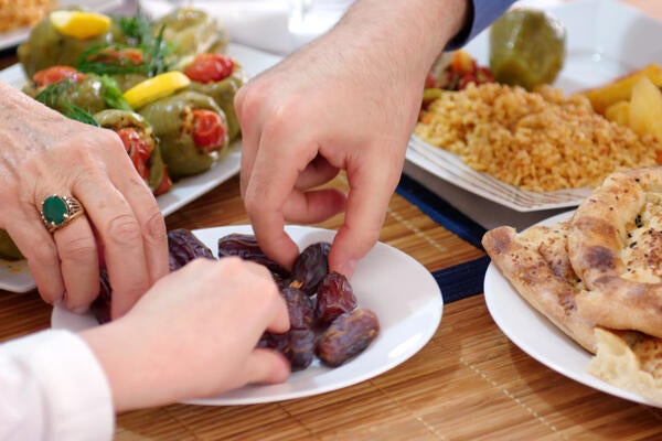 Three hands reach for a plate of dates.