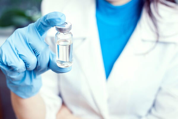 Pharmacist holds medical glass vial for vaccination. 