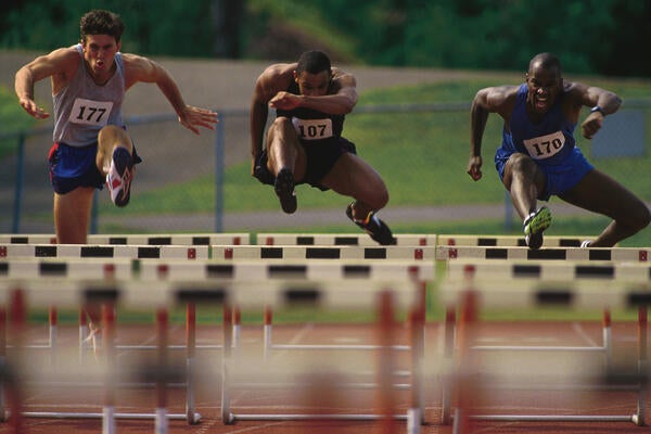 Runners jumping over hurdles 