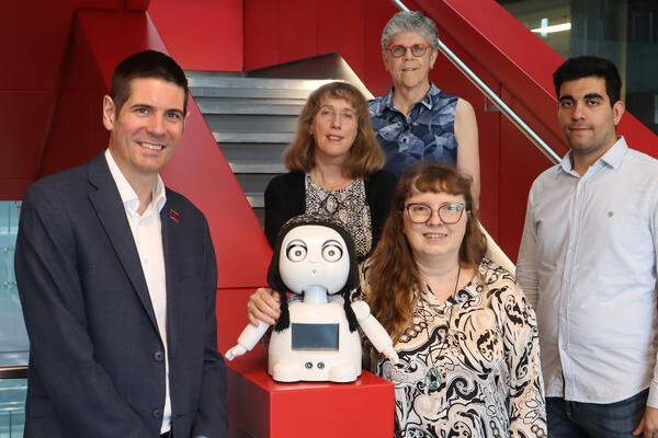 A group of researchers stand together with a social robot