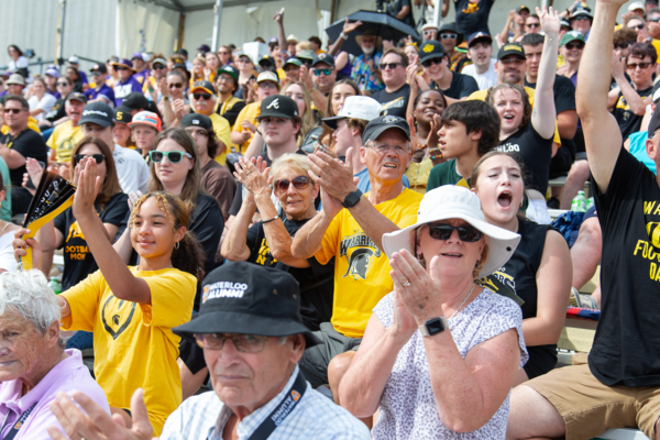 Attendees at the Homecoming football game cheering in the grandstands