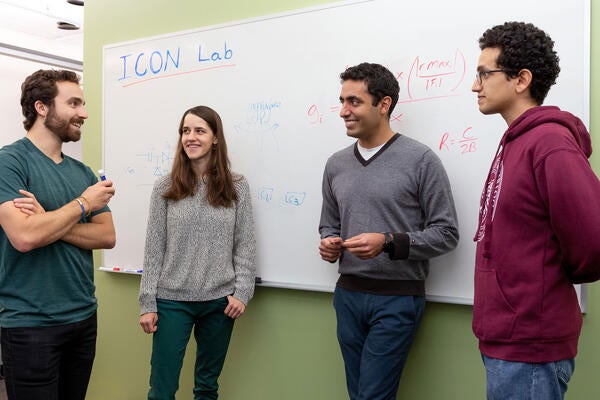 Professor Omid Abari and his students stand beside a white board