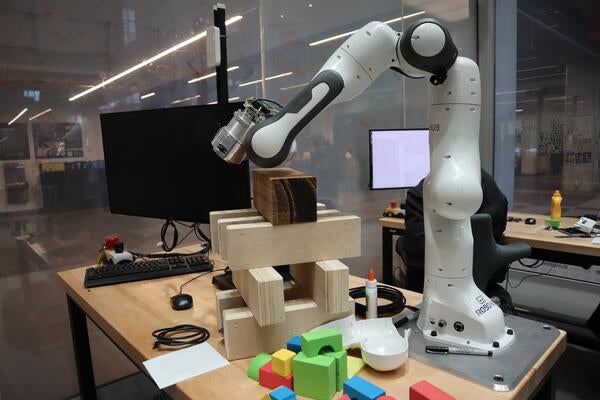 A photo of a robotic arm positioned over building blocks