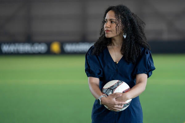 Dr. Kaleigh Pennock stands inside the field house holding a soccer ball
