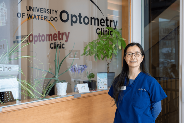 Dr. Lisa Woo standing in front of a window decal thay says "University of Waterloo Optometry Clinic."