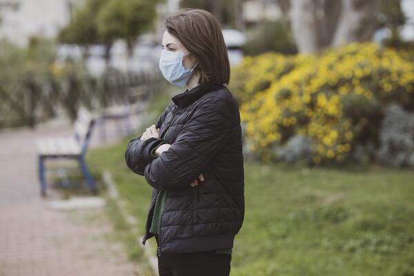Woman with folded arms wearing a COVID-19 mask.