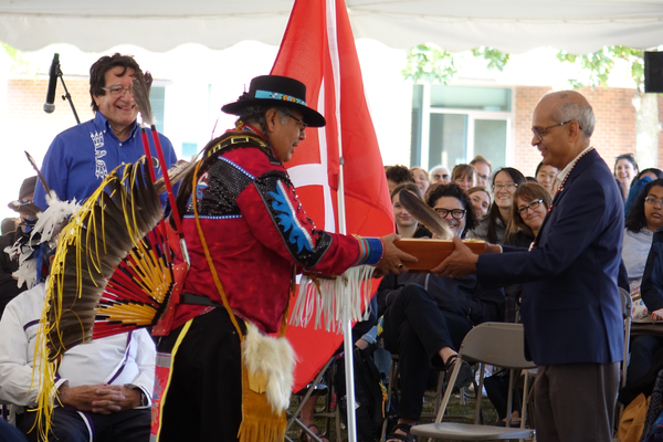 Vivek Goel, president and vice-chancellor of Waterloo, receiving the gift of an eagle feather from Elder Myeengun Henry