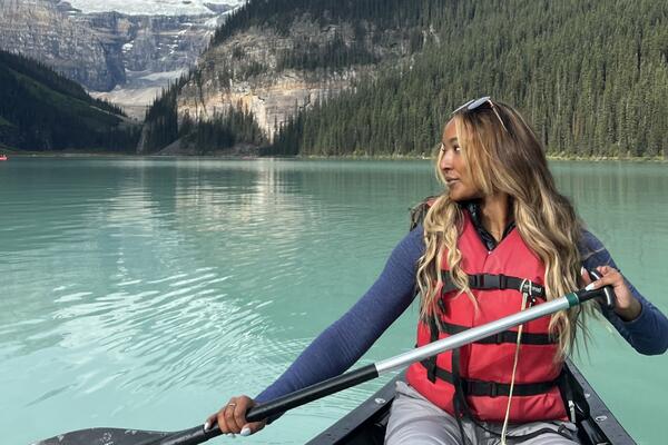 Marianna Sukhu paddles a canoe on a beautiful, clear lake while on a recreational trip.