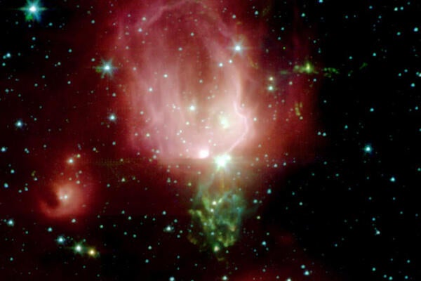 Star Forming region NGC_7129, a cloud of pink and green gas with balls of bright light inside. Stars around the outside