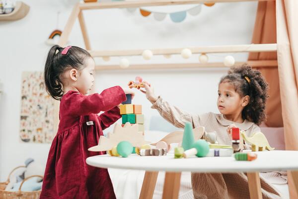 Two girls play with toys in a daycare centre