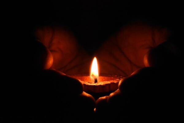 hands holding a small votive candle
