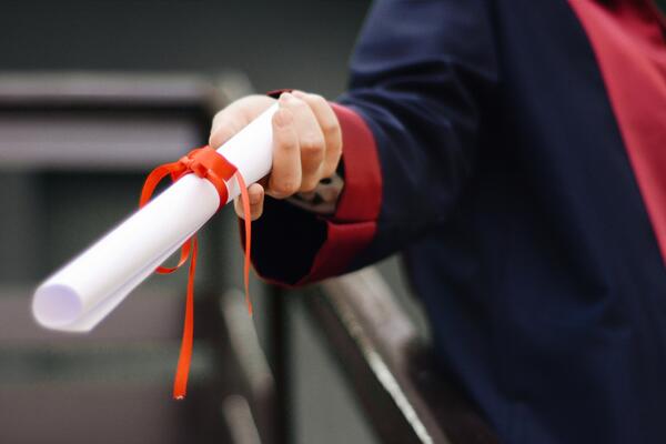 Hand holding out a graduation diploma