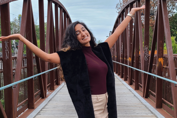 Preet Momi on a bridge with hands thrown up in celebration