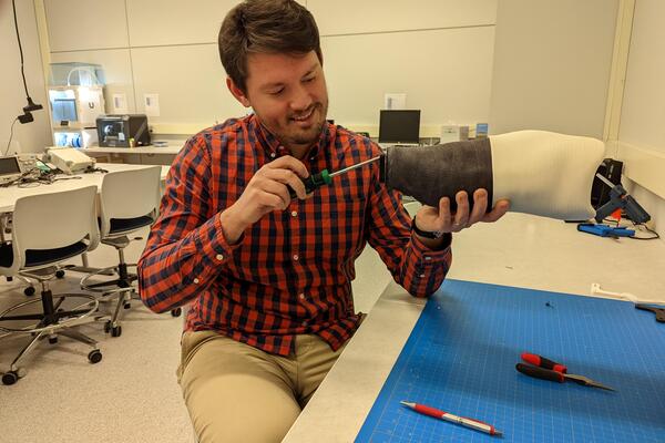 A man working on adjustments of a prosthetic limb in a lab setting.