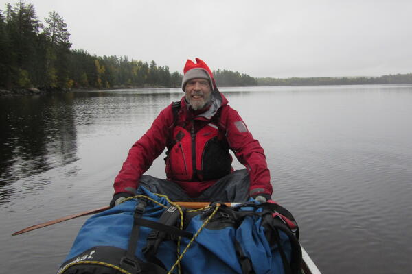 Murray smiles from the back of a canoe, paddle in hand