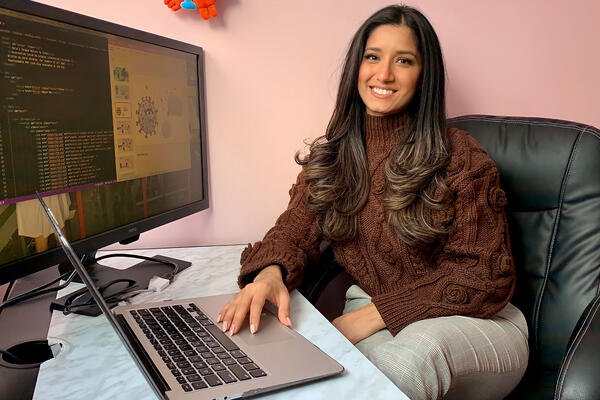 Sara Ibrahim sitting at her computer, looking at the children's story