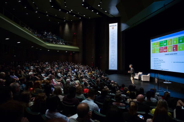 A large crowd of people gather in an auditorium