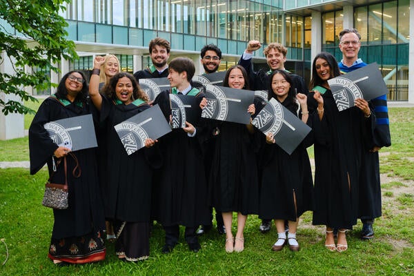 The Sustainability and Financial Management grads in their graduation robes holding up their diplomas