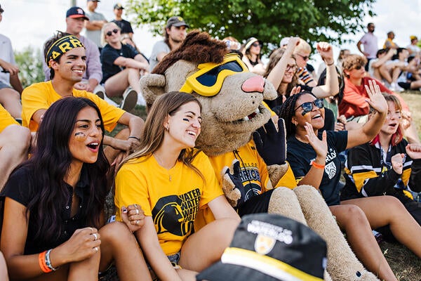 King Warrior sits with students at Black and Gold Day