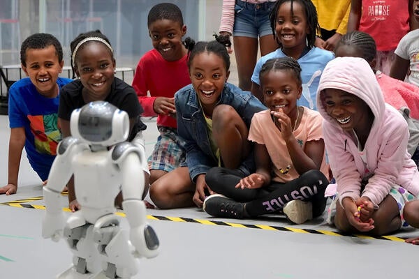 Children on Waterloo campus gleefully observing a mini robot