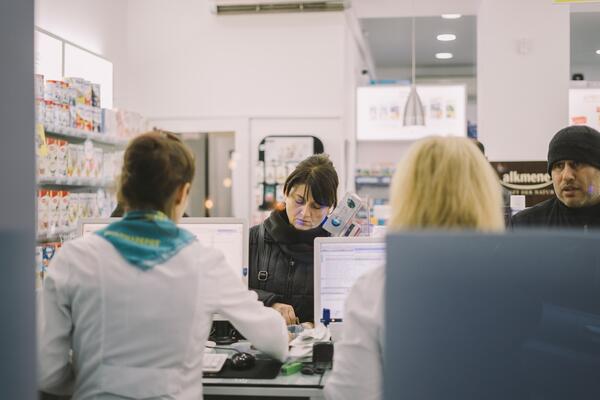 Pharmacists at a counter helping patients
