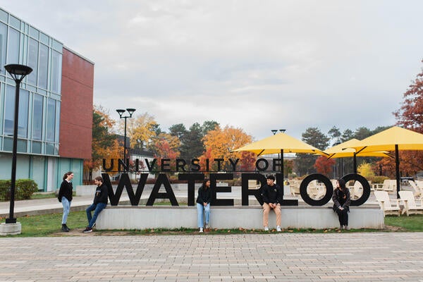 University of Waterloo students hanging out by the Waterloo sign