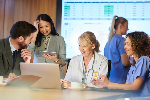 Medical professionals and hospital executives meeting with a giant screen in the background