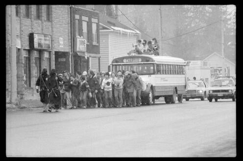 Black and white photo of students pulling a school bus