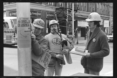 Black and white photo of people putting up signs