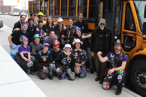 Students smiling in front of a school bus