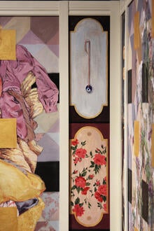 A corner of the exhibit featuring panels containing flowered wallpaper and an evil eye necklace