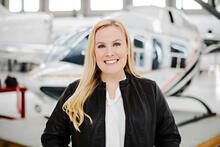 Suzanne Kearns stands smiling in front of a helicopter.