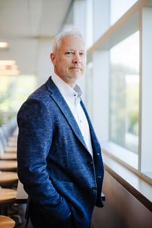 man stands in front of window with hand in pocket