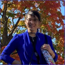 Dr. Dario Ho wearing a blue blouse and silver-framed glasses