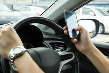 Image of hand holding phone while driving