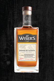Bottle of JP Wiser's Dissertation whisky against dark wood background