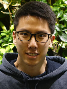 Quinlan Lee smiles at the camera wearing a grey hoodie.