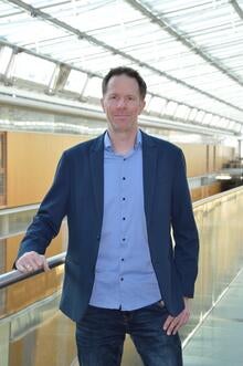 standing man with right hand resting on railing
