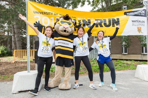 Friends pose with King Warrior in front of the Fun Run banner