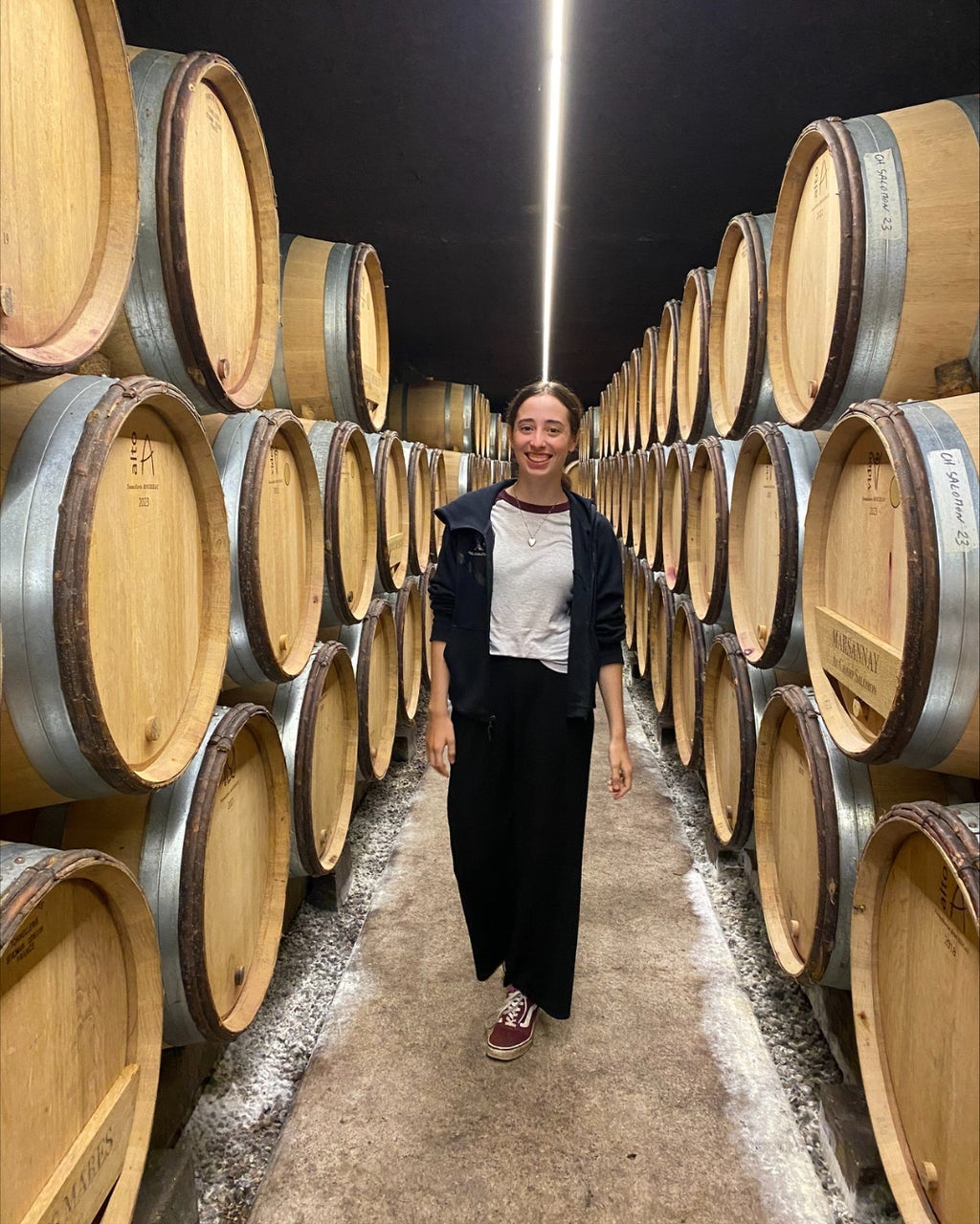 Charlotte standing in a row of wine barrels