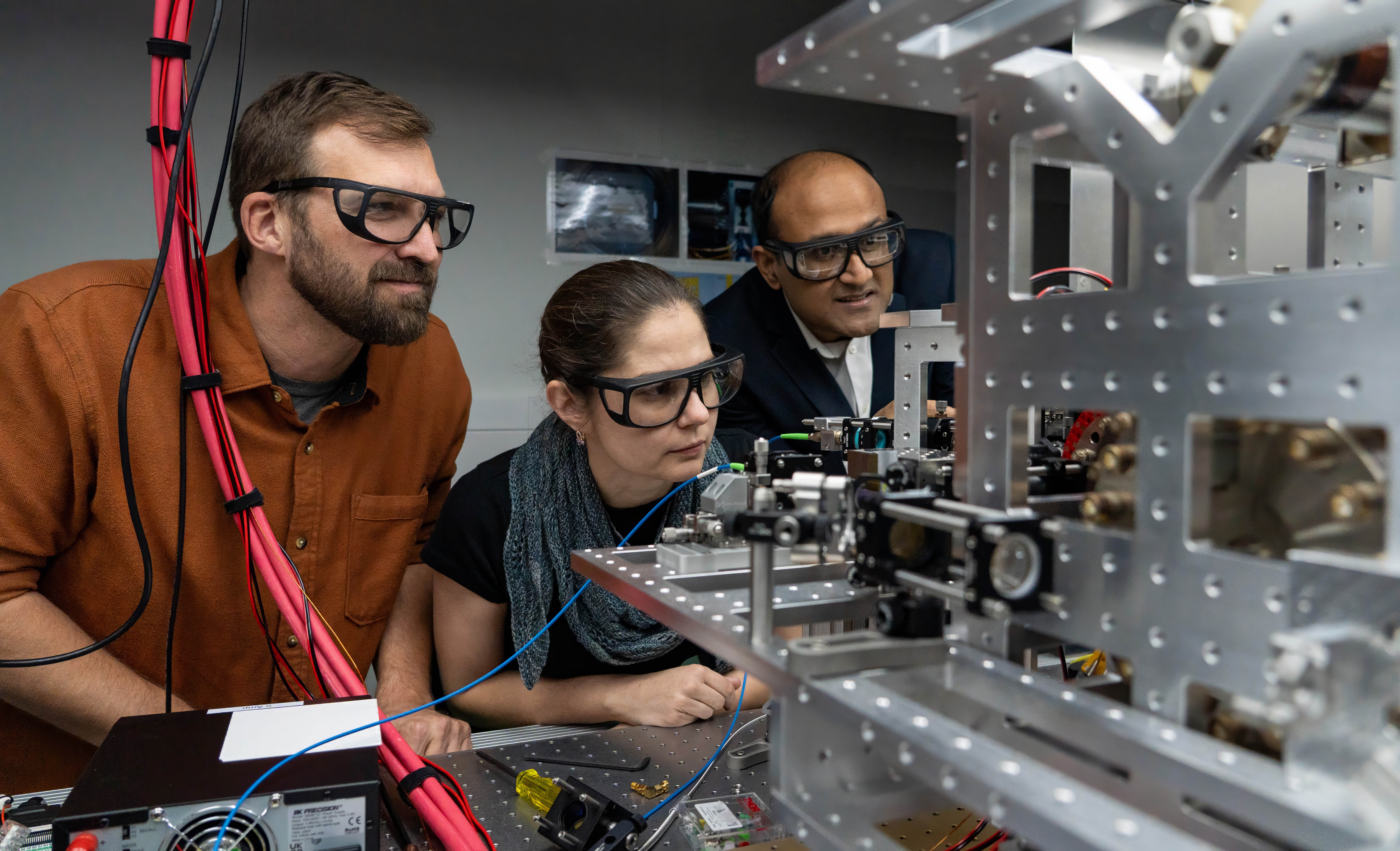 Cystal Senko intently examines OQD unit with Roger Melko and Rajibul Islam