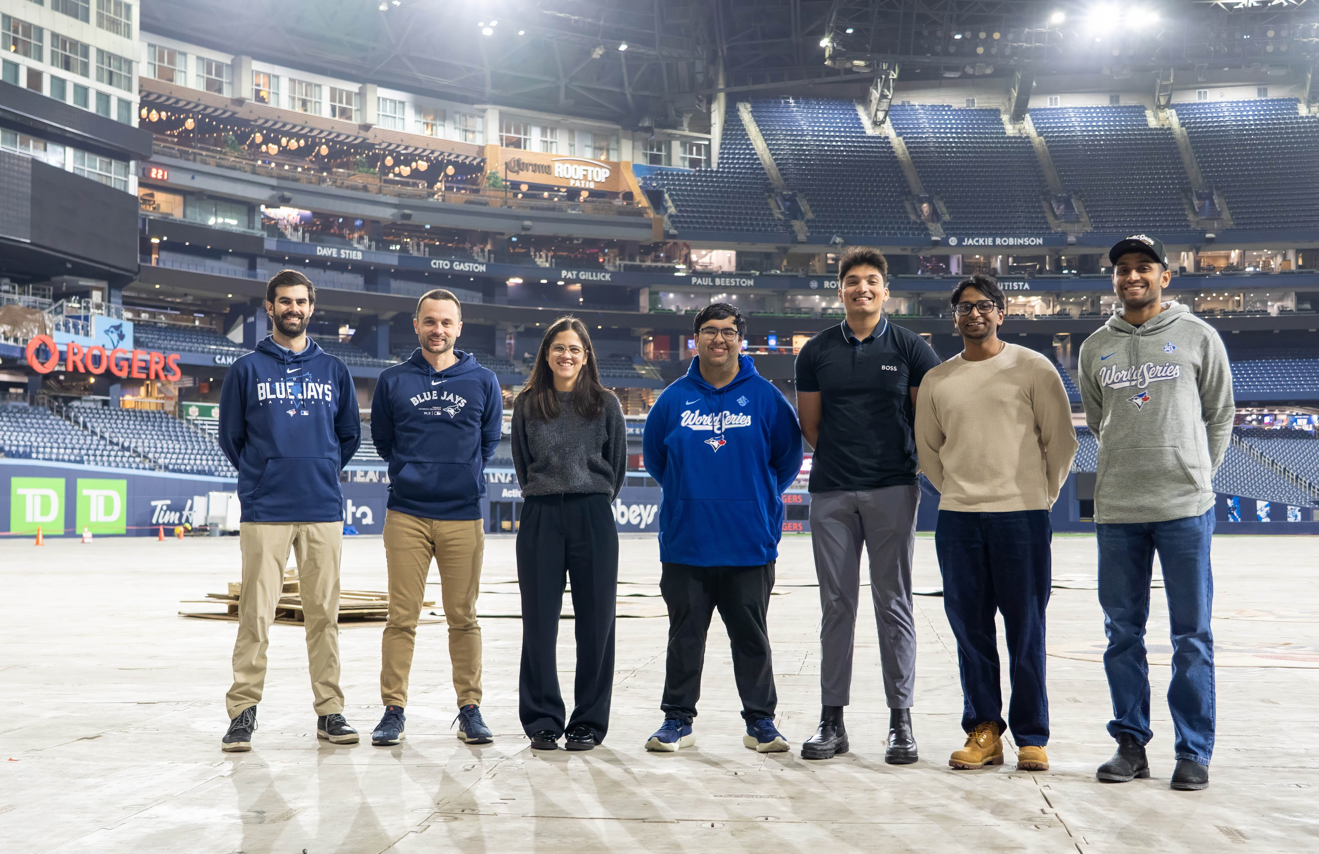 Group of people stand with arms crossed on field at Rogers Centre