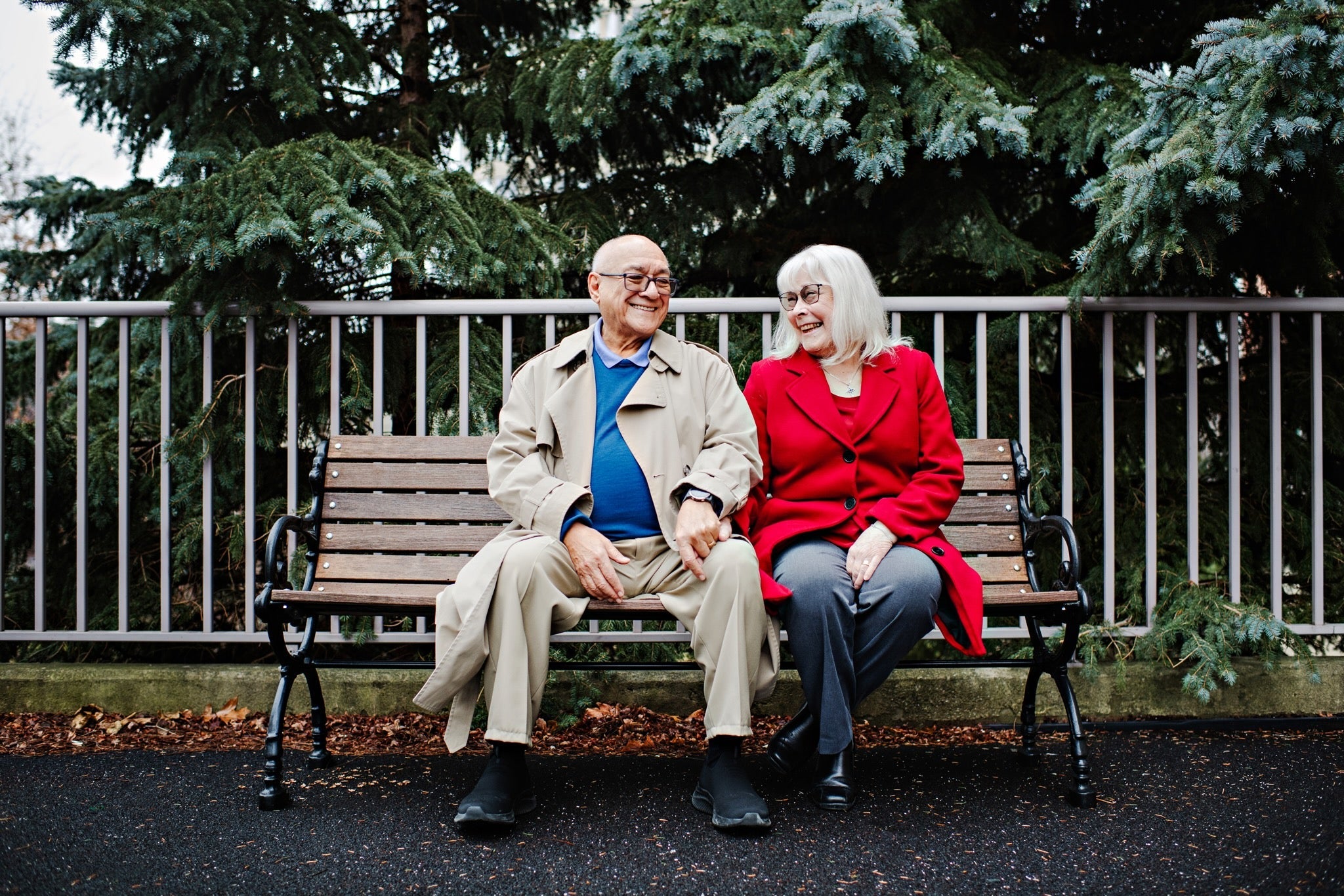 Gil sits on a park bench with his wife
