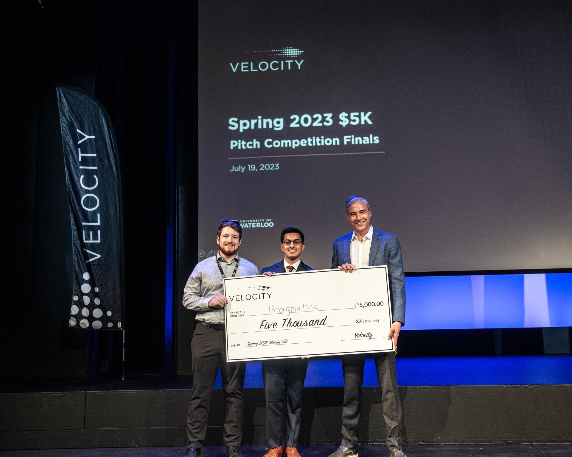 Two students pose with John Dick holding a novelty check