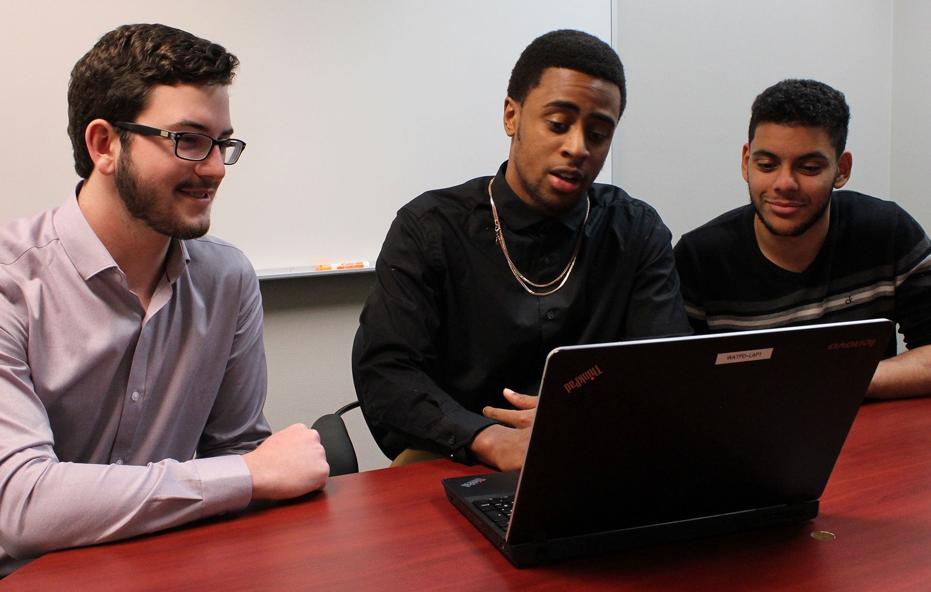 Aaron Cole talking with colleagues as they look at a computer.