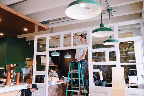 Adam Shwartzentruber puts finishing touches on a reclaimed window wall he built and installed for the new Settlement Co. in Ayr Ontario. Photo by Caitlin McWilliams