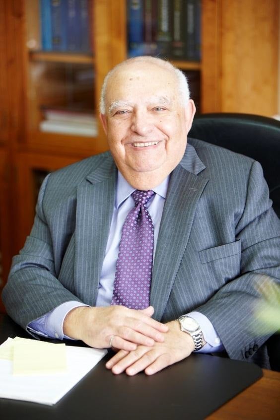 Dr. Adel Sedra seated at a desk with papers in front of him.