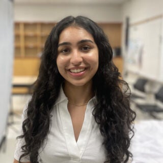 A young woman smiles in a classroom