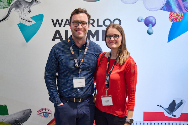 Alumni pose in front of a Waterloo Alumni backdrop